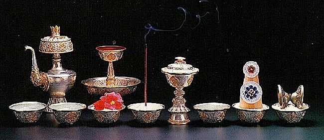 The eight sensory offerings from left to right are: water for drinking, water for washing (the feet), flowers for beauty, incense for smell, light (candles, buttlerlamps or light) for seeing, perfumes, food for eating, and sound or music for listening.