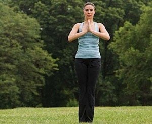 Woman standing in meditation with hands held in prayer