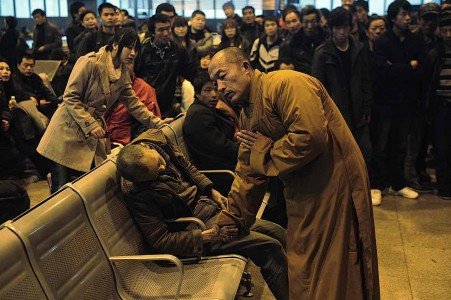 A monk holds the hand of a deceased person found on a train platform in China. 