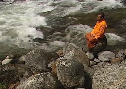 Zasep Rinpoche meditates by a river in British Columbia.