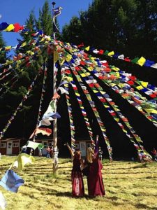 Buddha Weekly Lama Dr. Shannon Young teaching at a retreat with prayer flags Buddhism