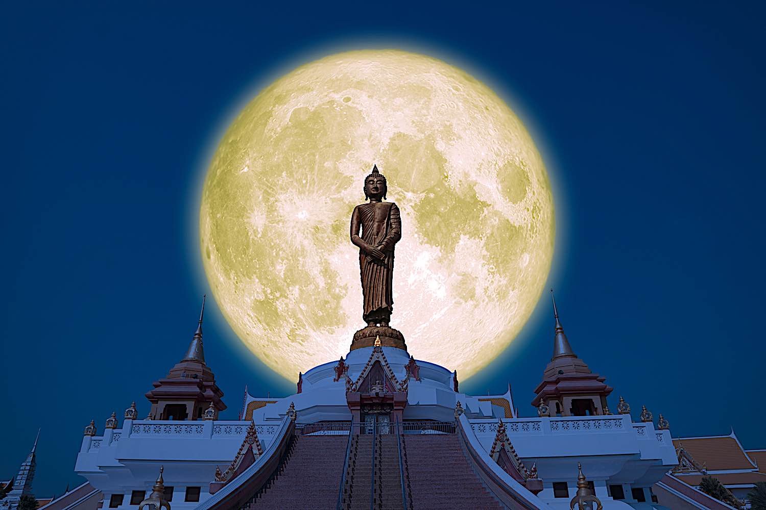 Buddha statue against a full moon.