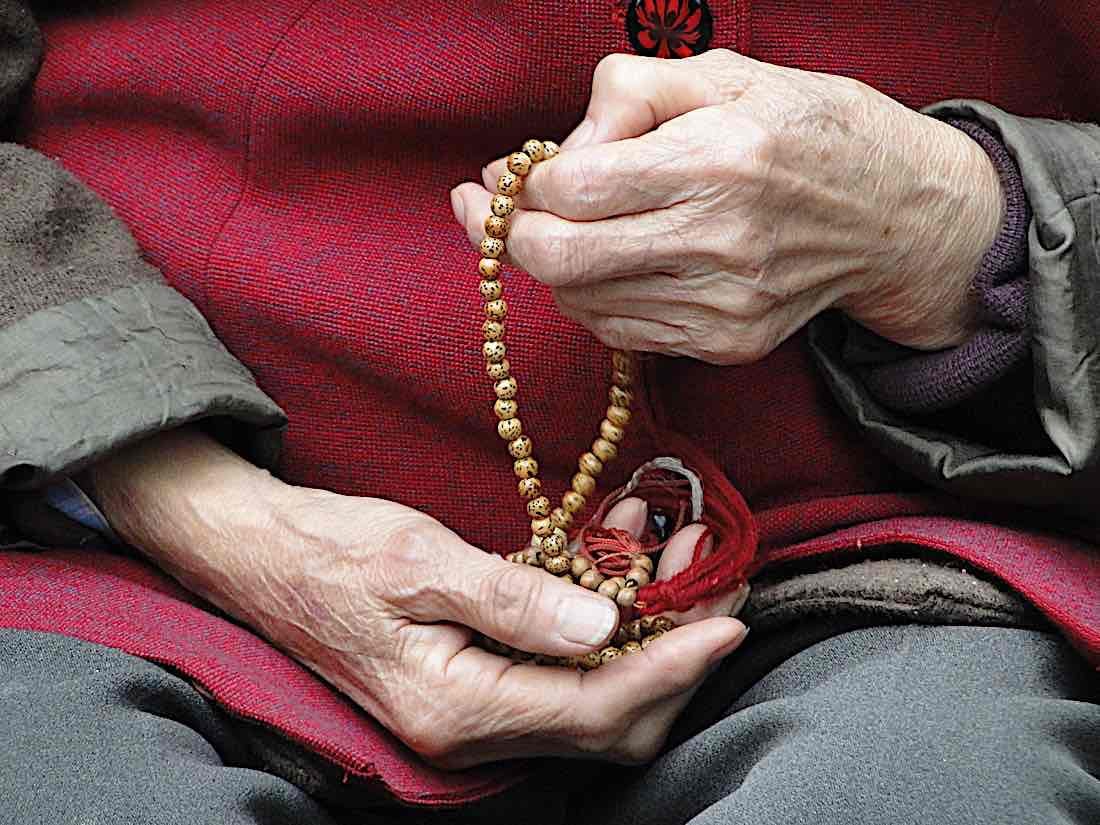 Prayer beads wrapped round the wrist of a red-robed monk