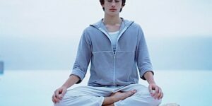 A man in lotus posture meditating on a dock.