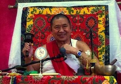 H.E. Garchen Rinpoche teaching with spinning prayer wheel in right hand.