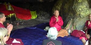 Buddha Weekly Zasep Rinpoche leading practice on Heart Sutra near Vulture Peak in sacred cave India praying Buddhism custom crop