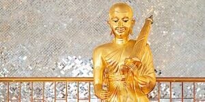 Gold Phra Sivali Bhante Statue. His famous attributes are he is walking, with an walking stick, begging bowl, beads and and umbrella on one shoulder.