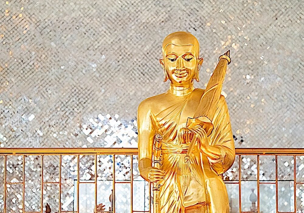 Gold Phra Sivali Bhante Statue. His famous attributes are he is walking, with an walking stick, begging bowl, beads and and umbrella on one shoulder.